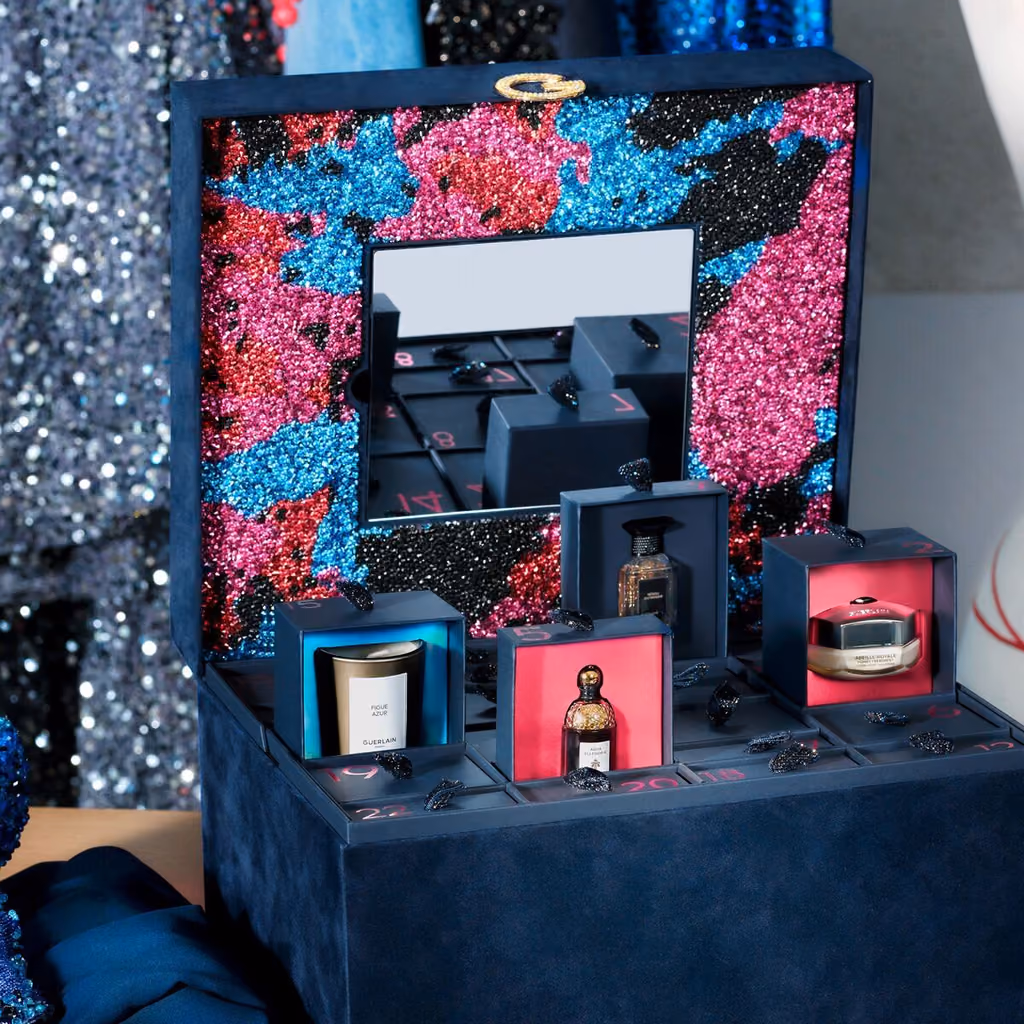 The beaded interior of the box with its mirror and three drawers open on a candle, a bottle and a cream
