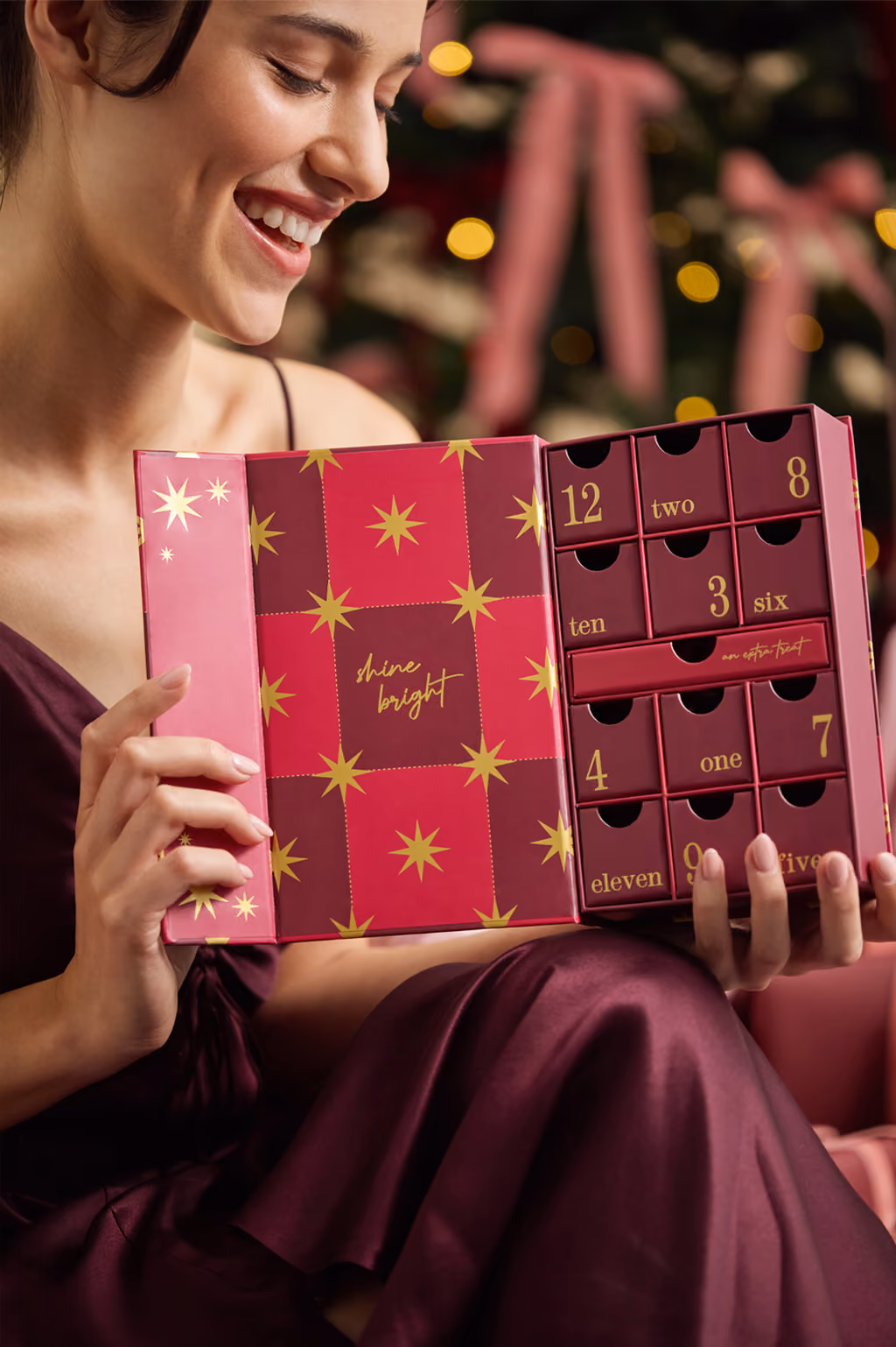 A woman holding the open calendar in front of a Christmas tree
