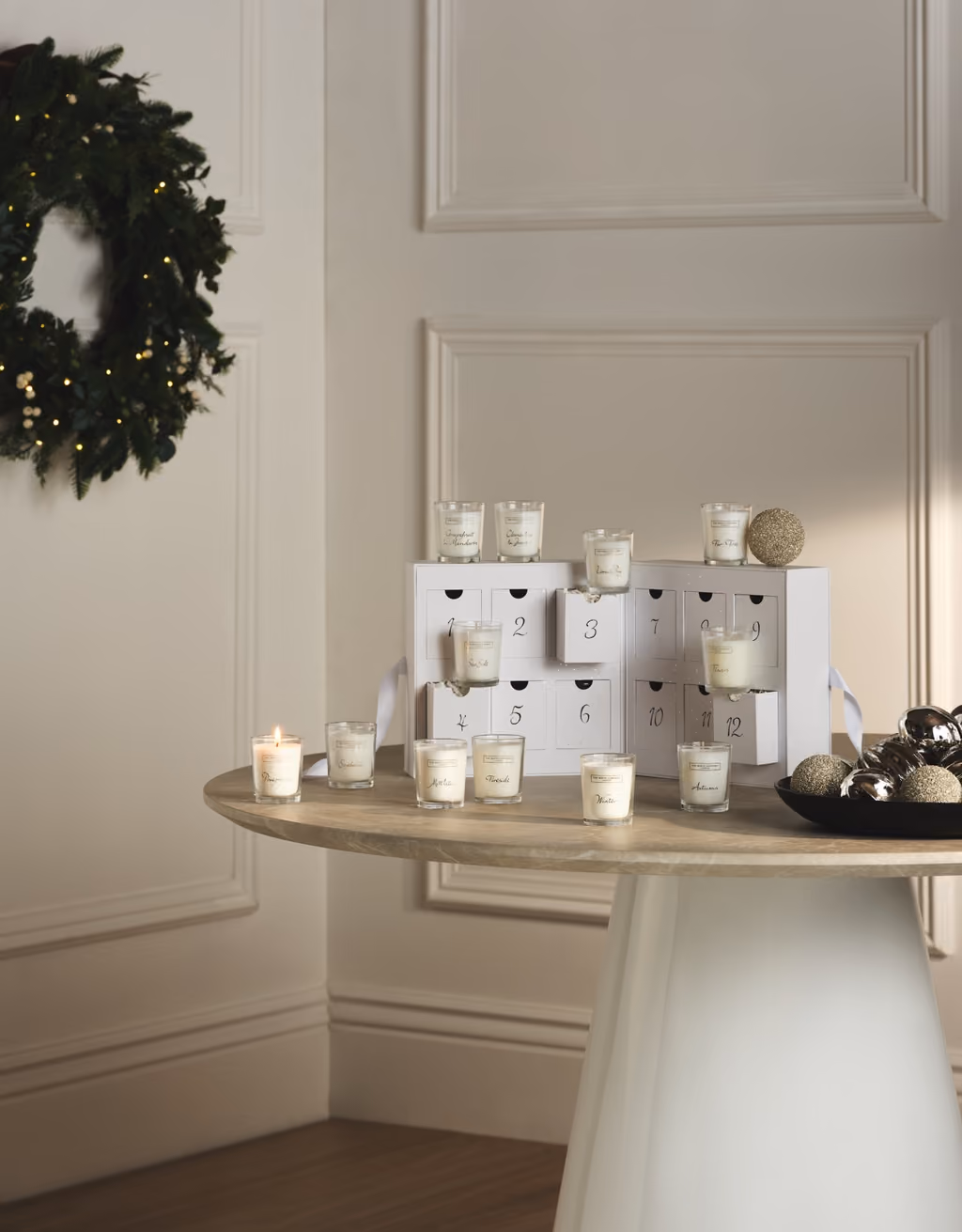 The open drawer box on a round table with the votives set out around it, one lit