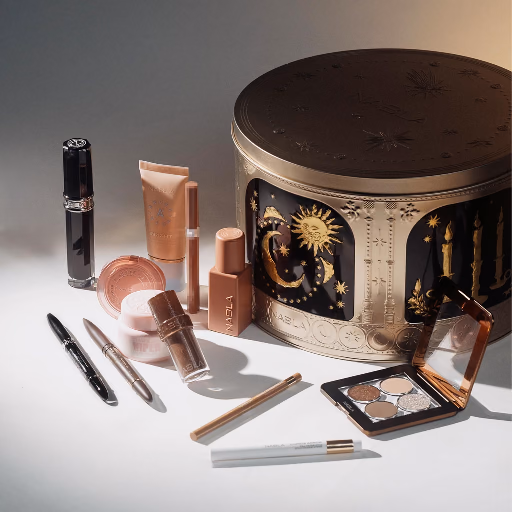 The tin with its lid on and the products spread around it on a grey ground