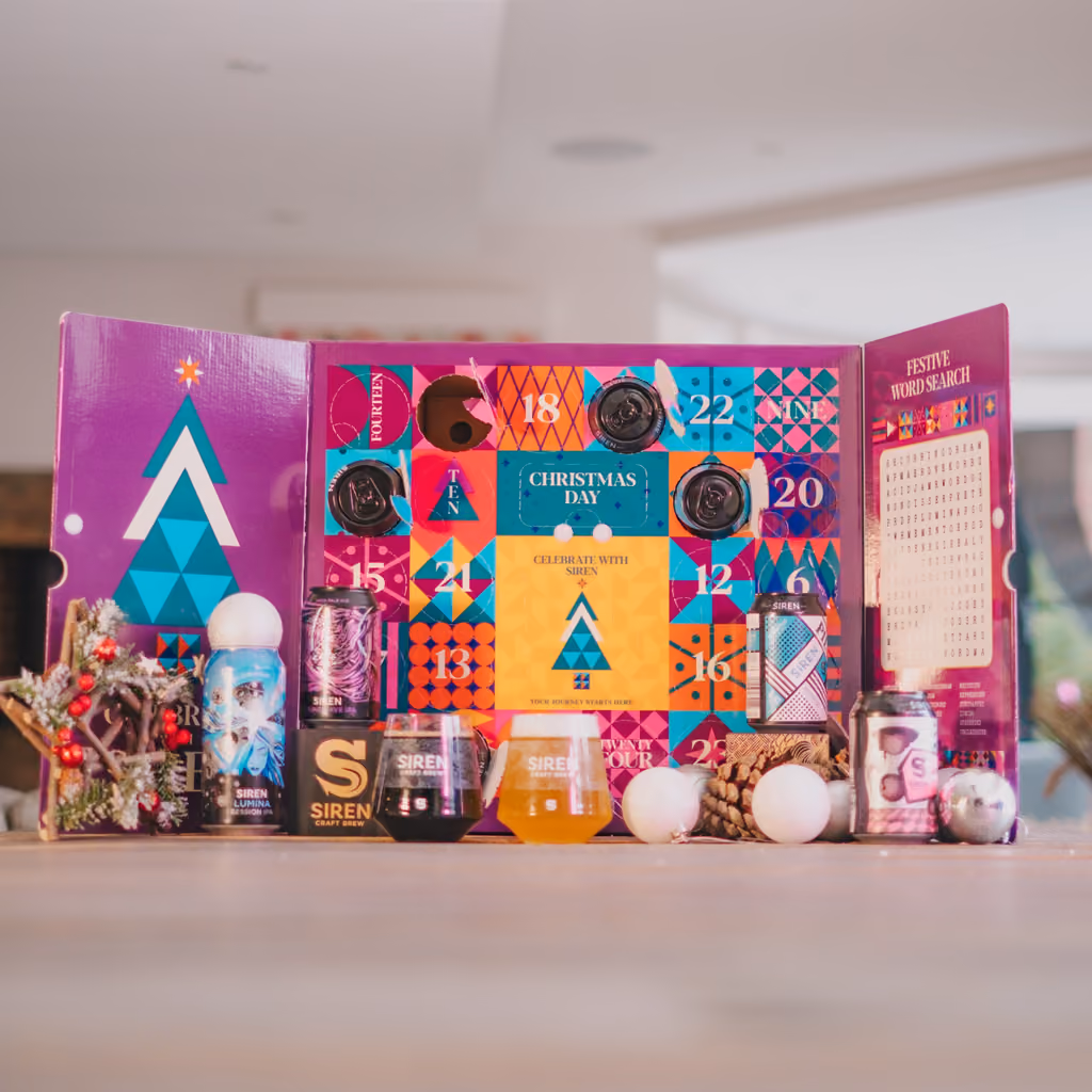 The calendar opened out with cans, a glass and baubles in front