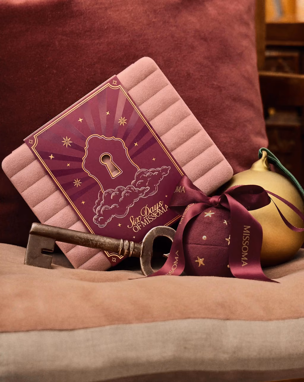 The closed Missoma box on a cushion with a key and baubles