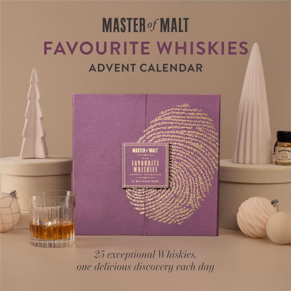 The purple box with a gold thumbprint on a beige set beside a tumbler and a dram