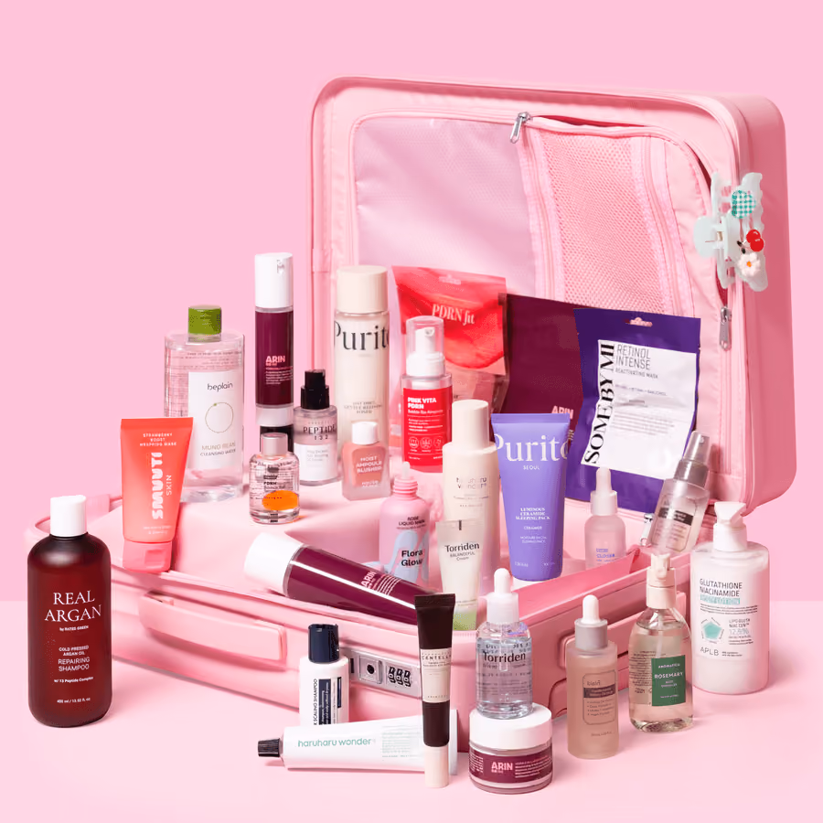 The pink suitcase open with the 28 products lined up in and around it