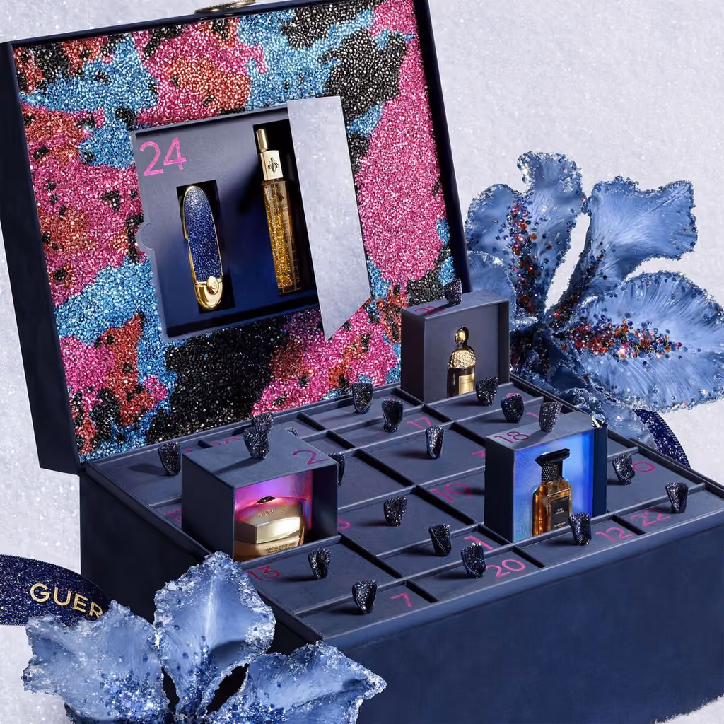 The Guerlain x Germanier jewellery box open on snow, drawers pulled out with miniature bottles and a lipstick in the lid