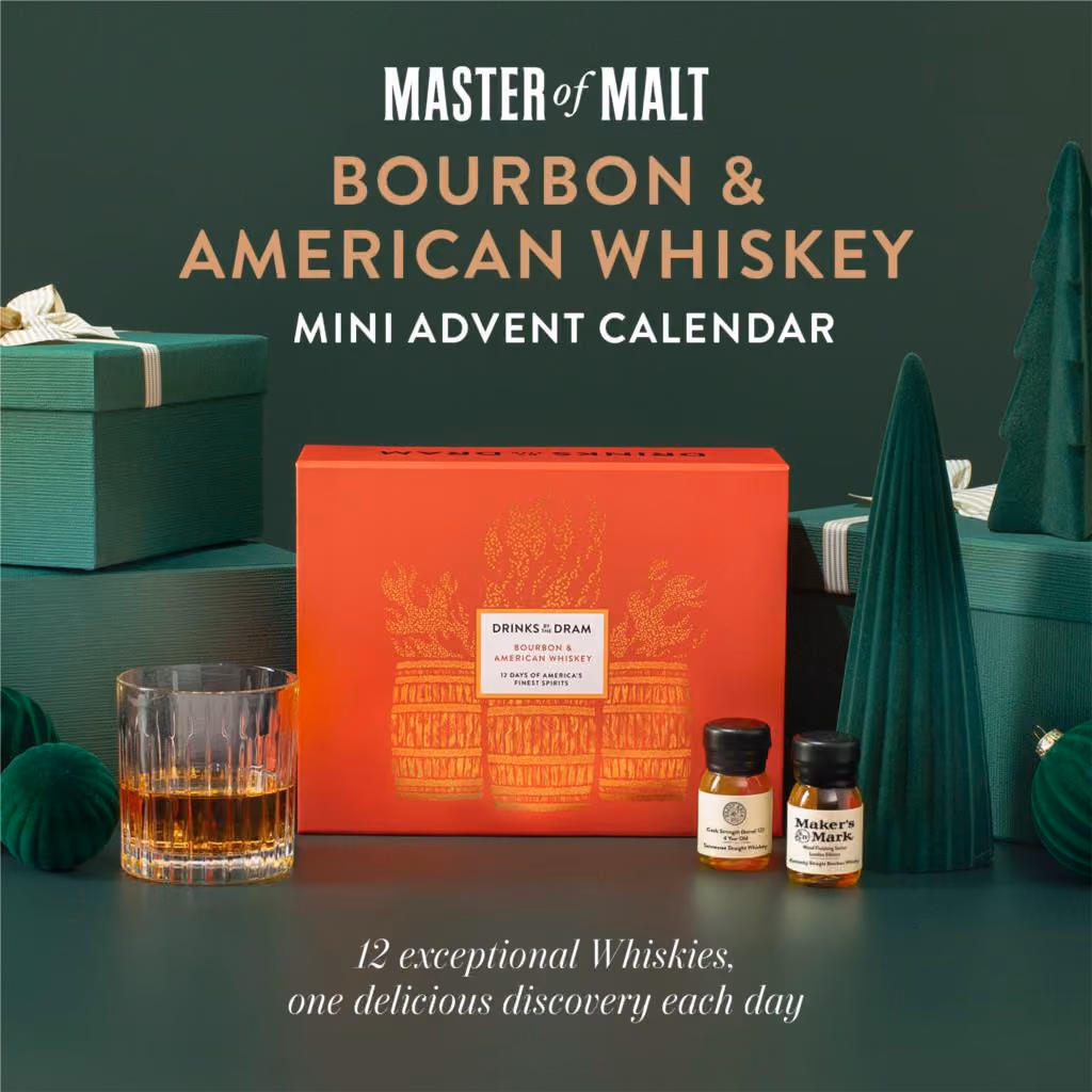 The orange mini box printed with barrels on a green set beside a tumbler and two drams