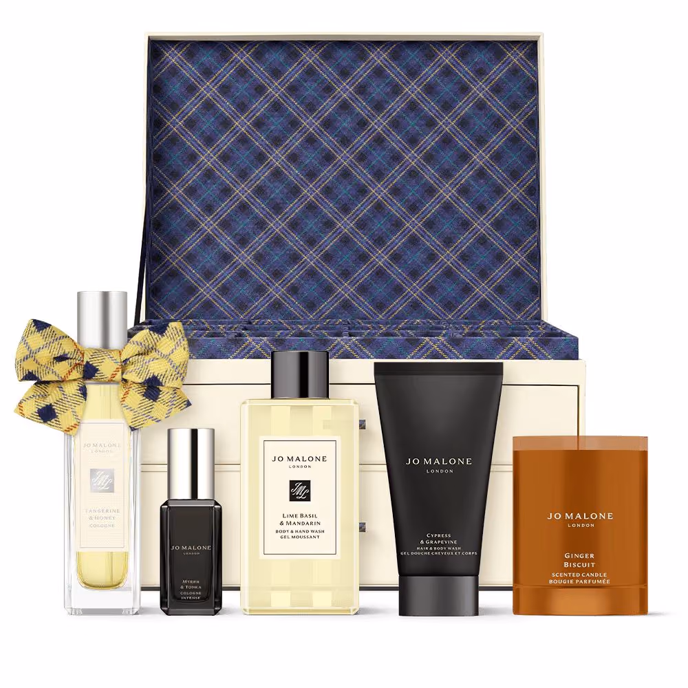 The Christmas Kist trunk with colognes, a candle and body products in front of it