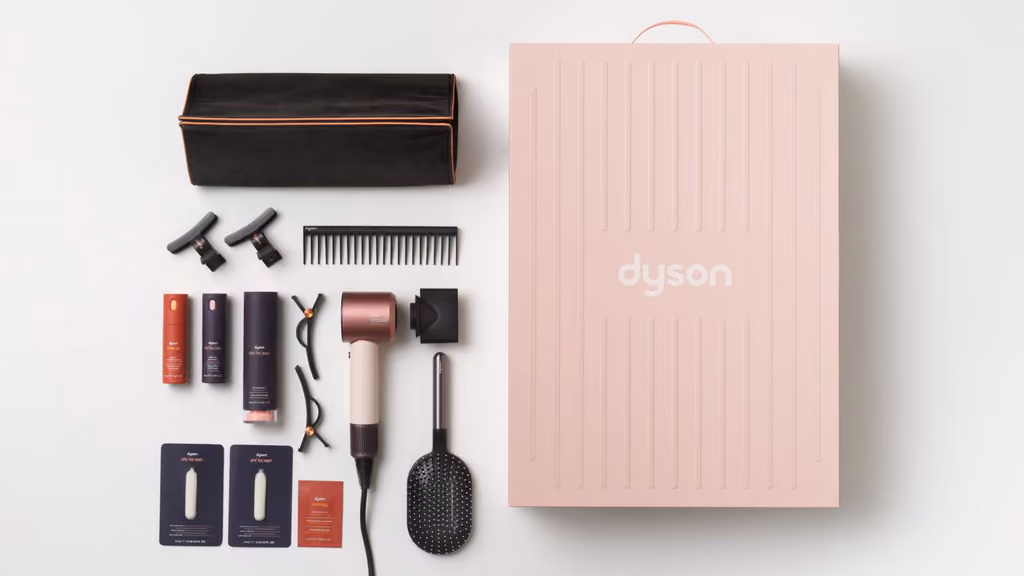 A woman drying curly hair with the pink Supersonic Travel, and the dryer in its black bag