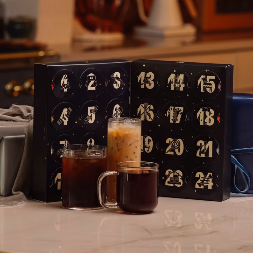 The open box behind an iced coffee, a black coffee and a cup of hot coffee