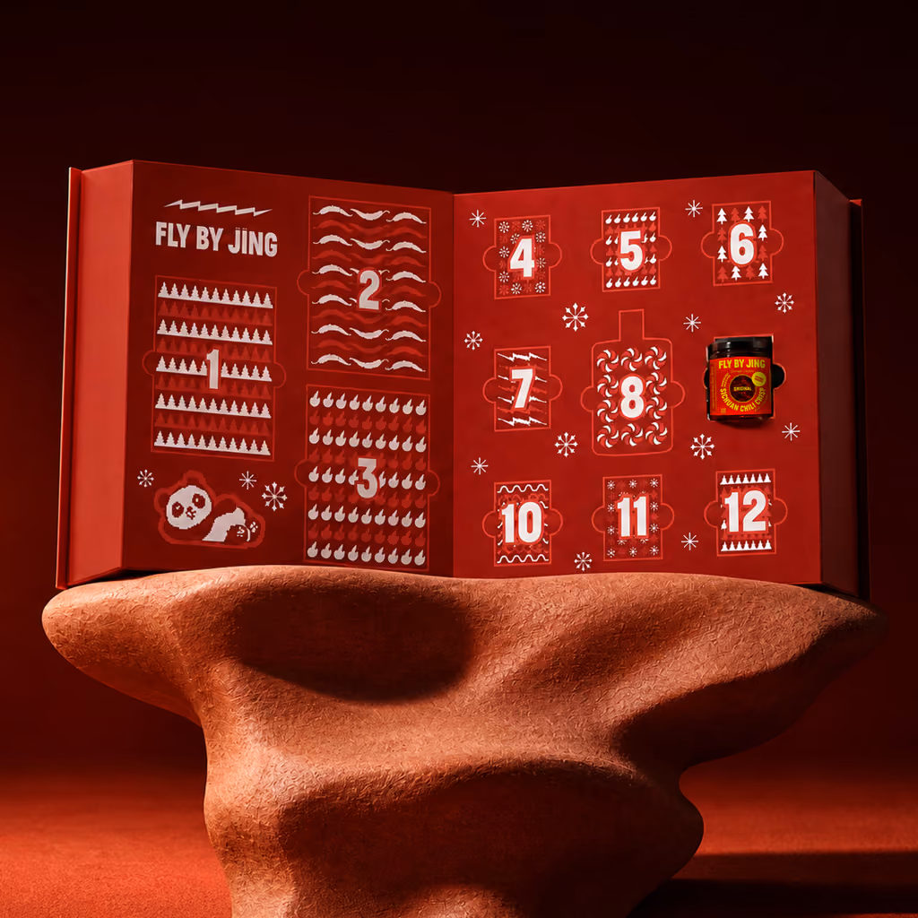 The Fly By Jing 2026 calendar open on a stand, twelve numbered doors with a jar behind one of them