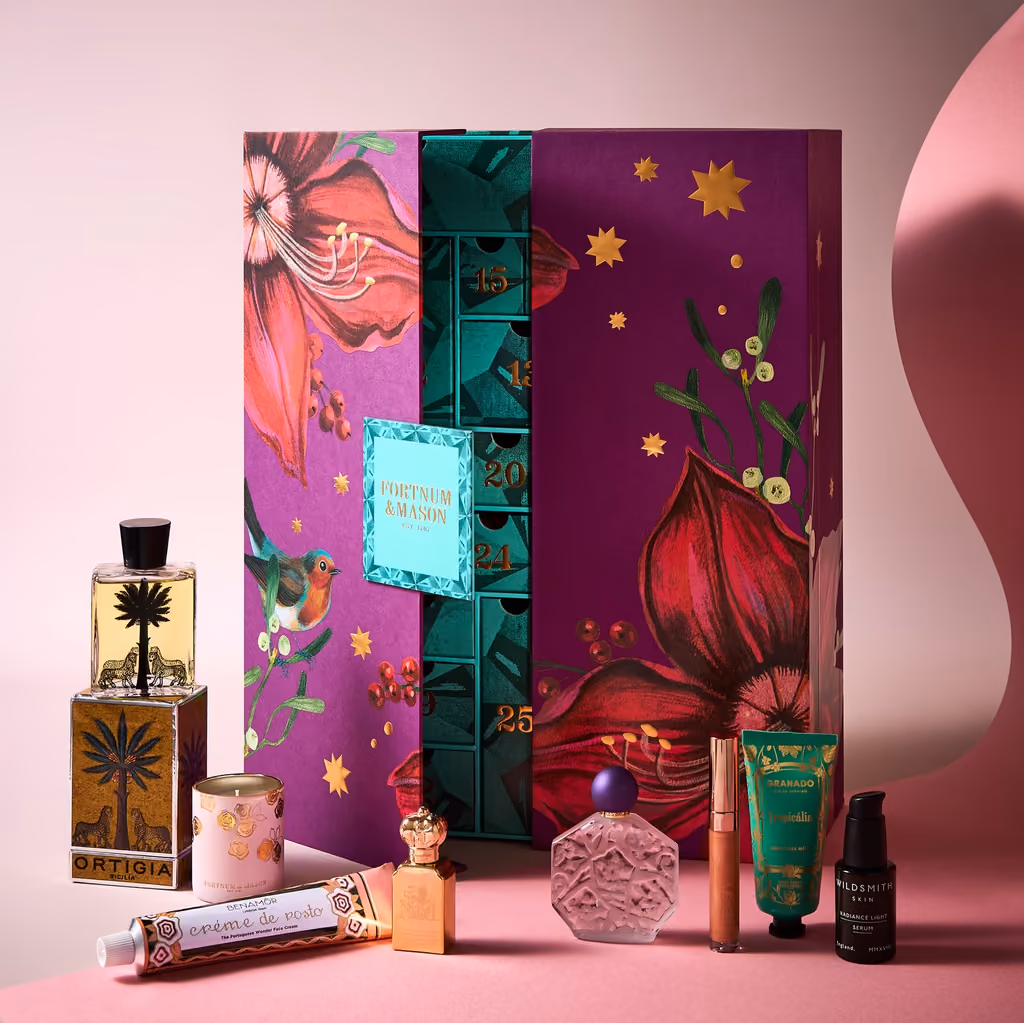 The box half open with fragrance bottles and skincare in front of it
