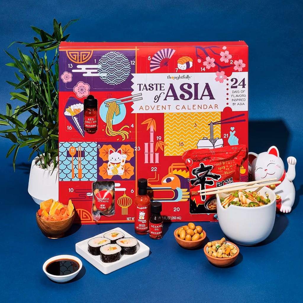 The box with a bowl of noodles, sushi and snacks in front