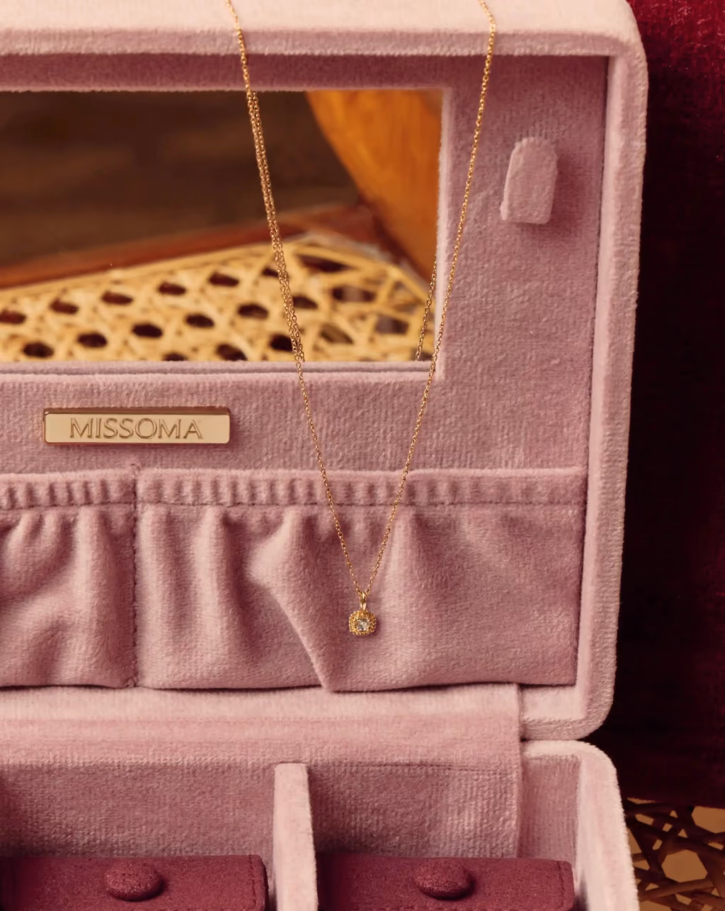 The closed Missoma box on a cushion with a key and baubles