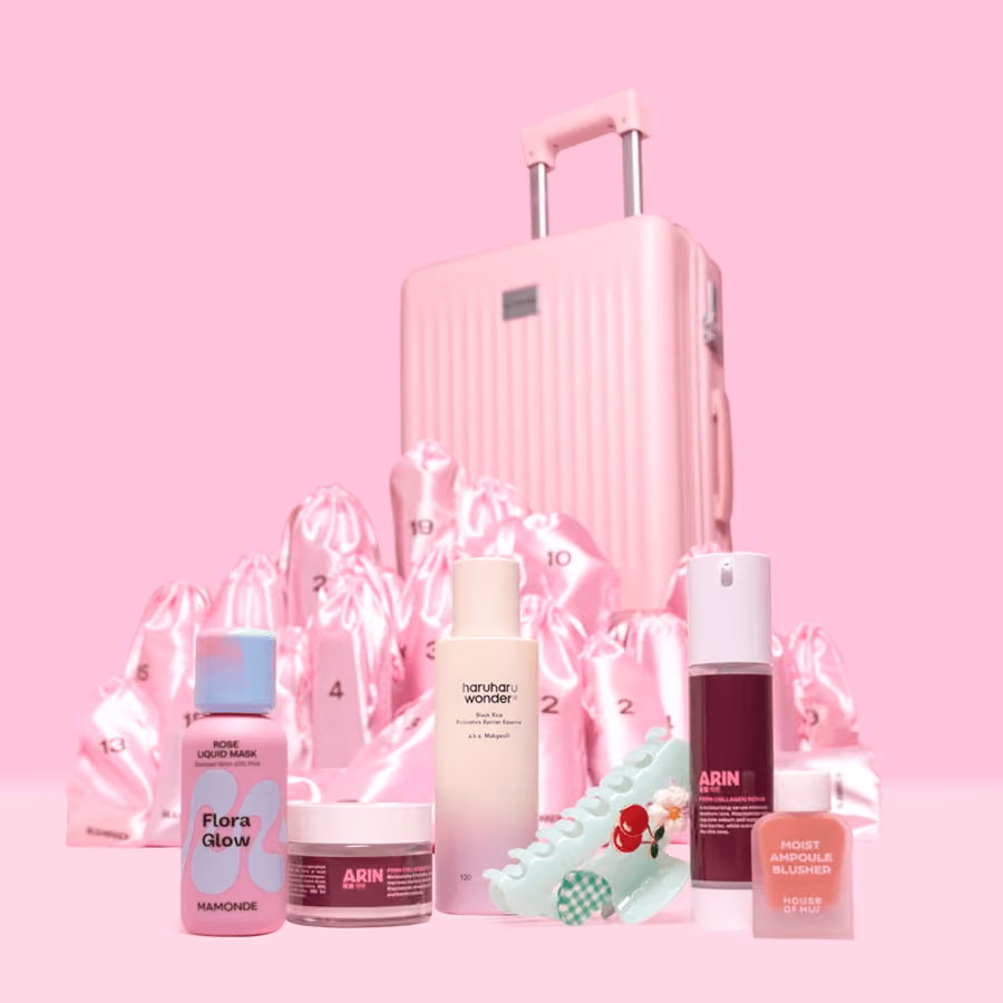 The closed pink suitcase behind satin pouches and a group of products
